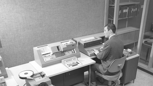 Schwarz-weiß Foto eines Mannes, der in den 1960er Jahren an einem Teil des Computers IBM System 360 arbeitet.