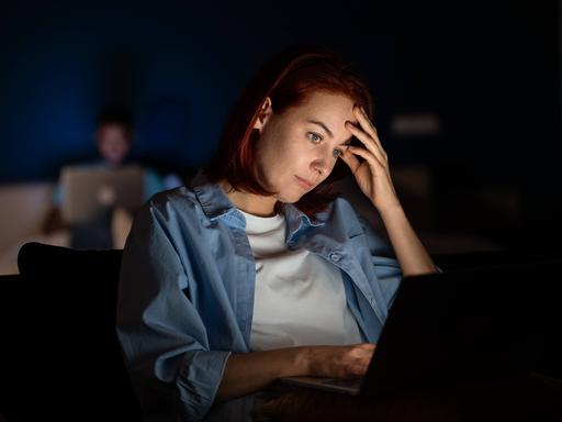 Eine Frau sitzt abends vor dem Laptop Eine Frau sitzt abends vor dem Laptop