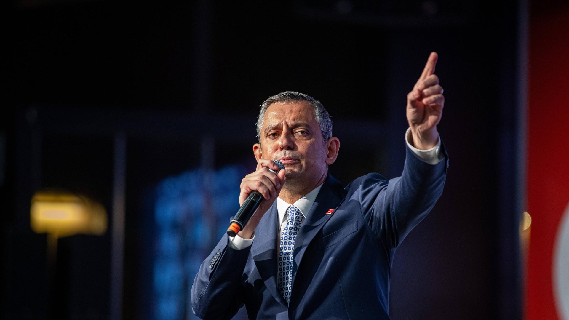CHP-Chef Özel spricht in ein Mikrofon, das er sich vor den Mund hält. Die andere Hand zeigt nach oben.
