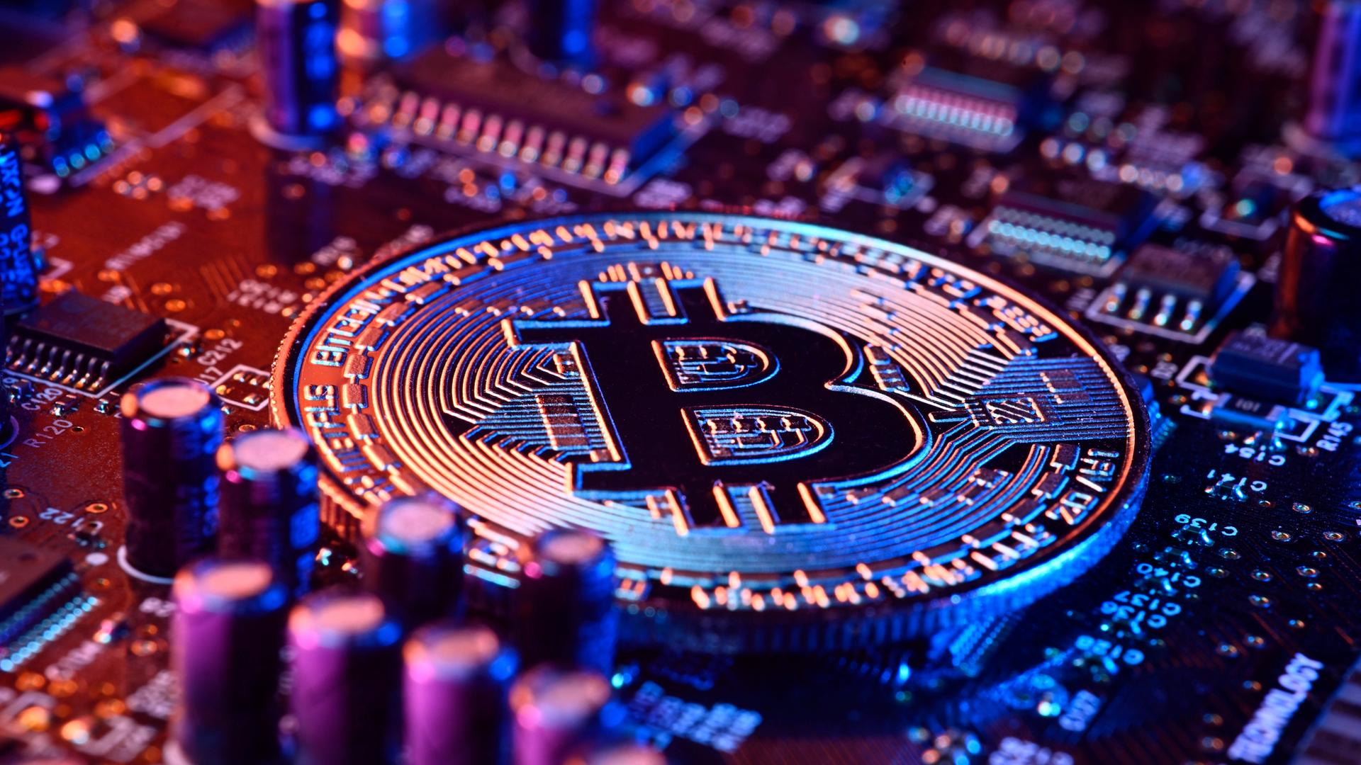 Bitcoin-Münze auf einer Computerplatine Bitcoin-Münze auf einer Computerplatine