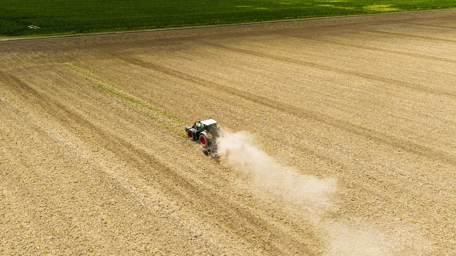 Trockenheit: Ein Landwirt fährt mit einem Traktor und einer Egge über ein Feld in der Region Hannover