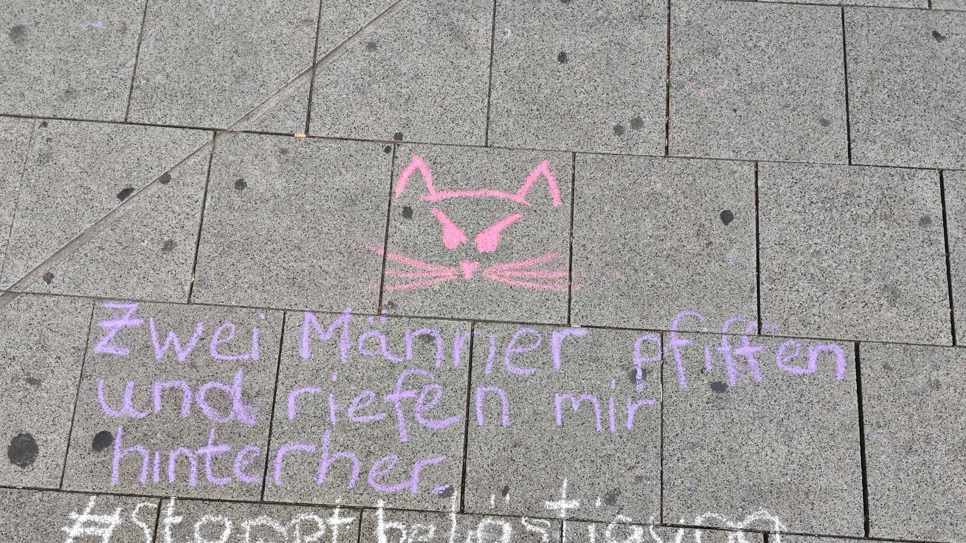 "Zwei Männer pfiffen und riefen mir hinterher - #stoppbelästigung" steht mit Kreide geschrieben auf einer Straße "Zwei Männer pfiffen und riefen mir hinterher - #stoppbelästigung" steht mit Kreide geschrieben auf einer Straße