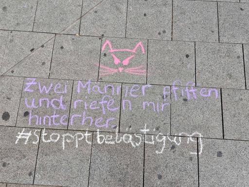 "Zwei Männer pfiffen und riefen mir hinterher - #stoppbelästigung" steht mit Kreide geschrieben auf einer Straße "Zwei Männer pfiffen und riefen mir hinterher - #stoppbelästigung" steht mit Kreide geschrieben auf einer Straße