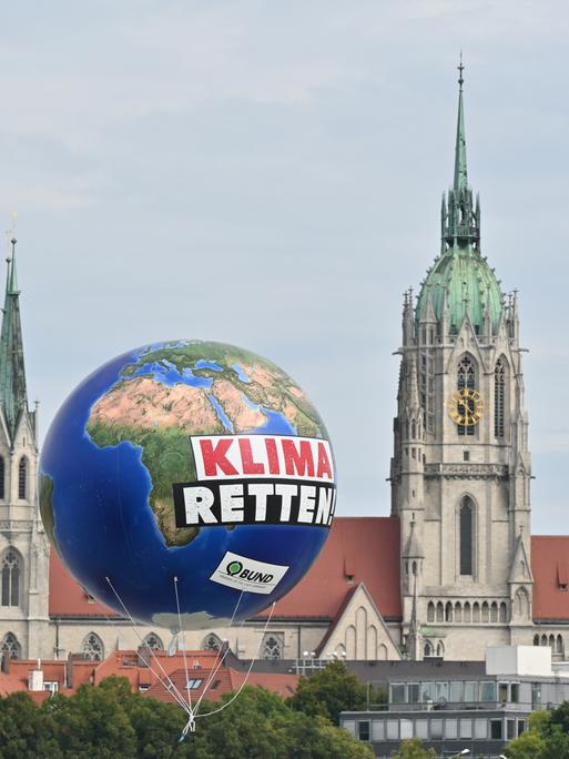 Ein Ballon mit der Aufschrift „Klima Retten“ schwebt vor einer Kirche