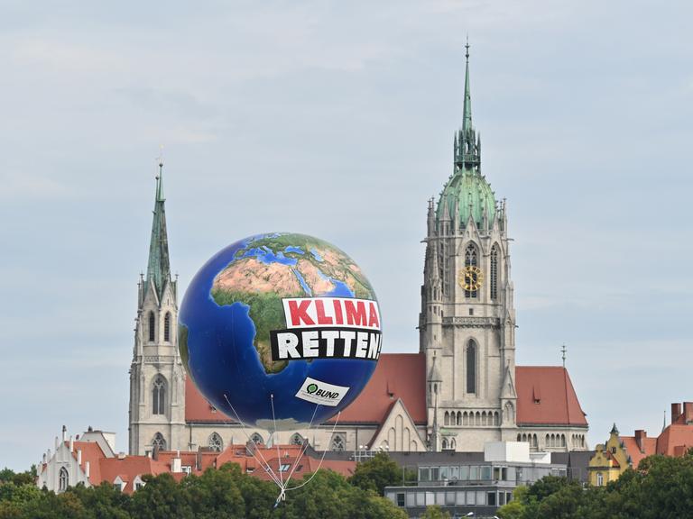 Ein Ballon mit der Aufschrift „Klima Retten“ schwebt vor einer Kirche