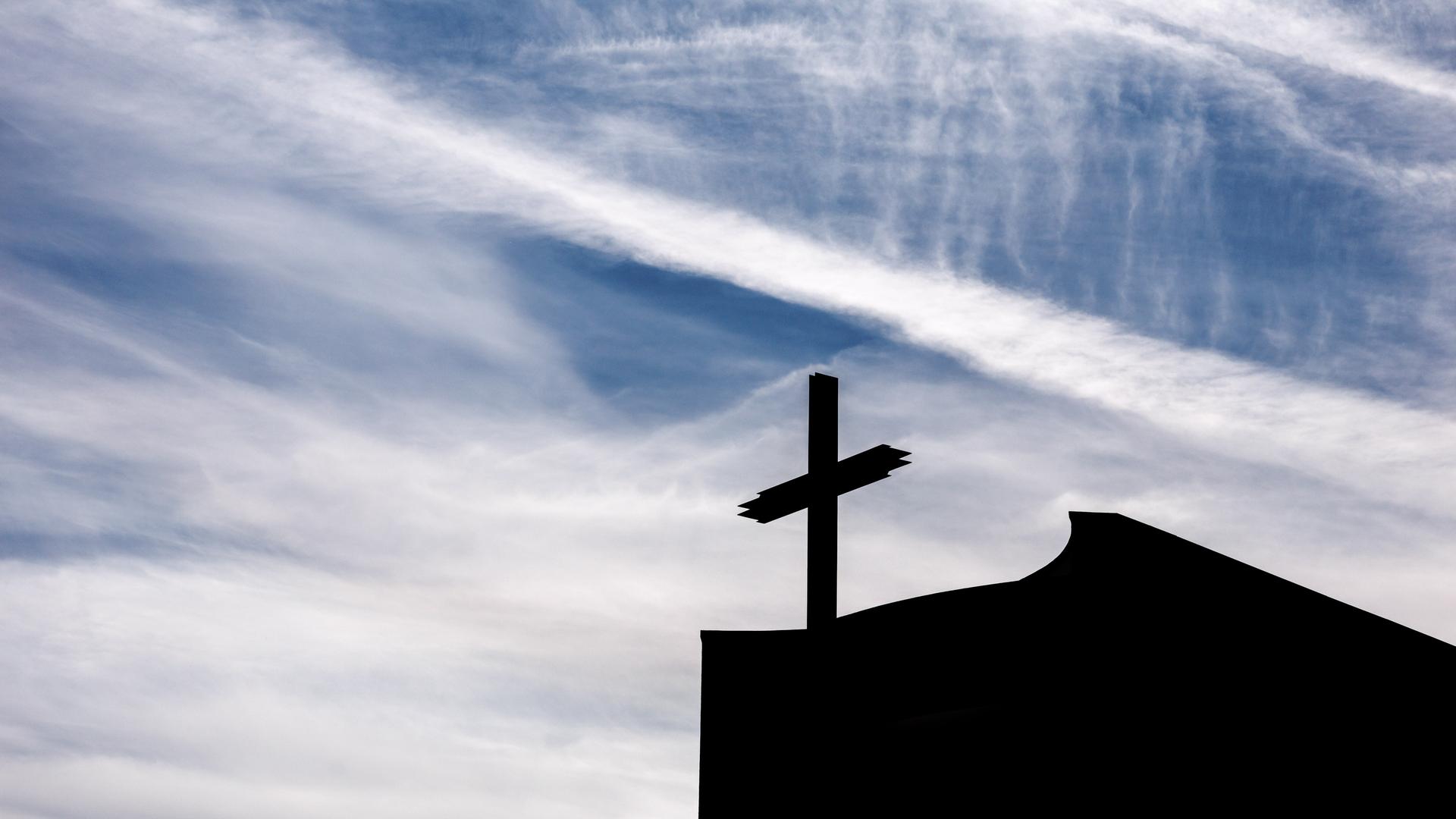 Ein Kreuz auf einer Kirche im Gegenlicht