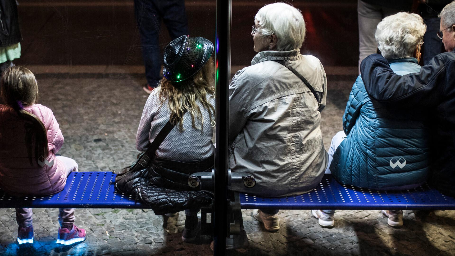 Junge und alte Menschen sitzen im Jahr 2018 auf der Bank einer Bushaltestelle in Berlin Junge und alte Menschen sitzen im Jahr 2018 auf der Bank einer Bushaltestelle in Berlin