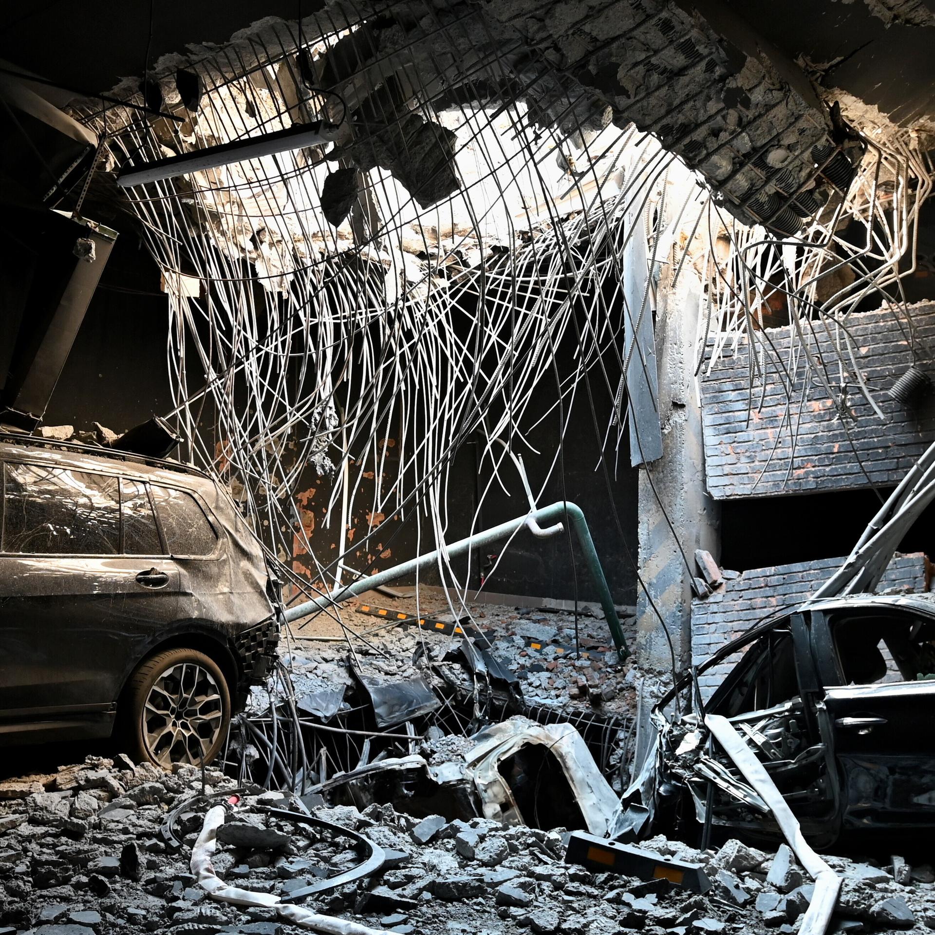 Kiew, Ukraine: Ein Loch in einer Geschossdecke durch eine Raketenexplosion und beschädigte Autos auf dem Parkplatz eines Wohngebäudes, das durch einen massiven russischen Raketenangriff beschädigt wurde.