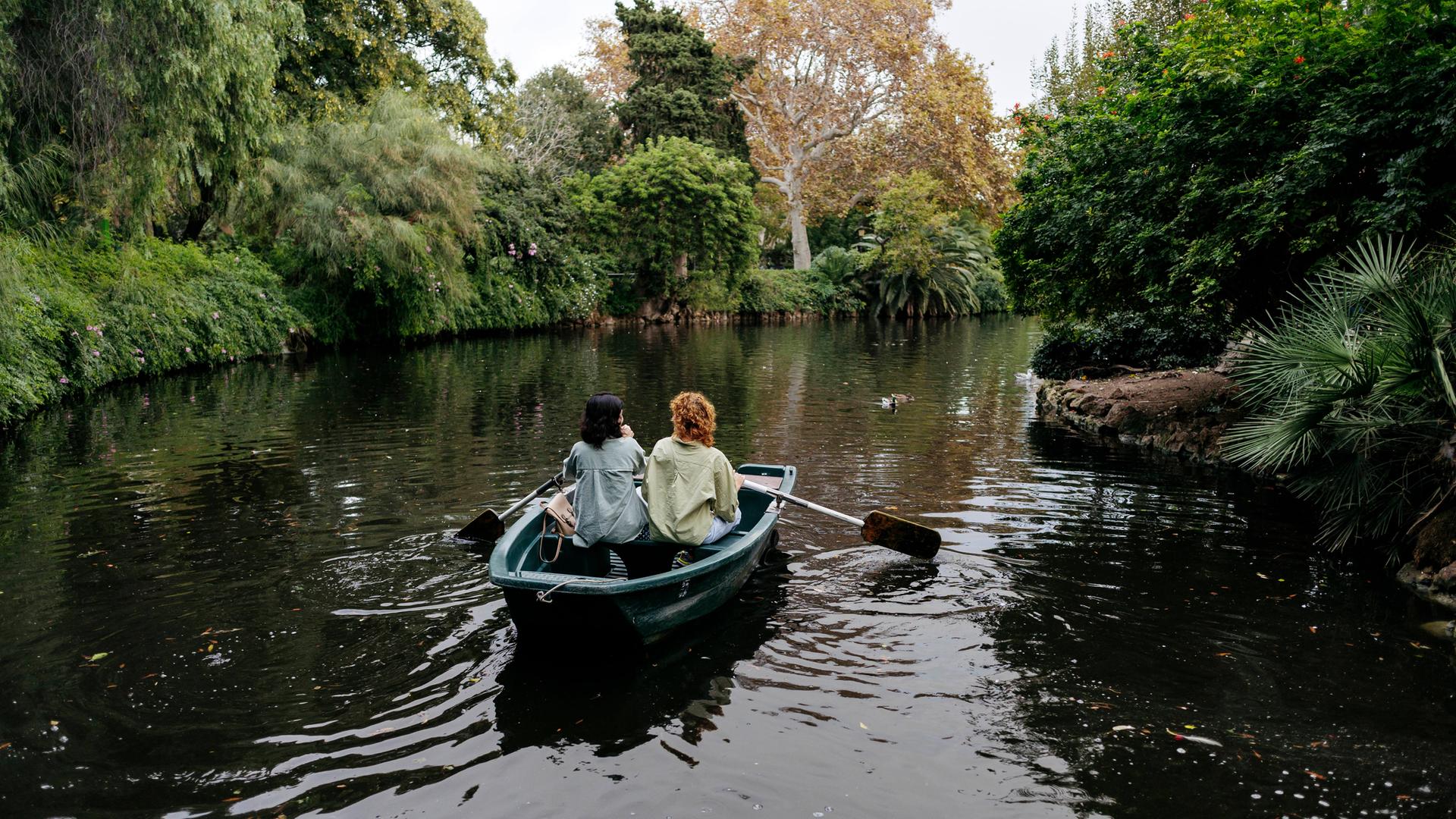 Lesbisches Pärchen in einem Ruderboot auf einem Weiher in Barcelona. Ringsum viel Grün. Lesbisches Pärchen in einem Ruderboot auf einem Weiher in Barcelona. Ringsum viel Grün.