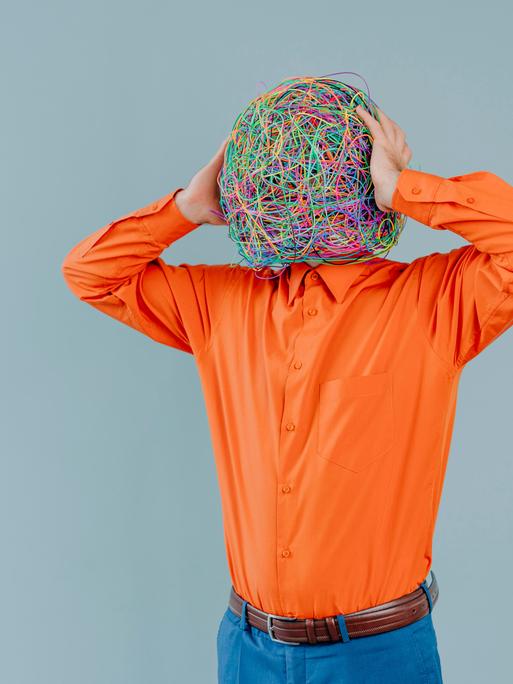 Frustrated man with mask of chaotic thoughts against blue background