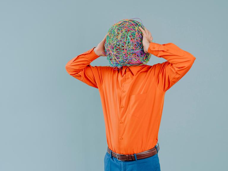 Frustrated man with mask of chaotic thoughts against blue background