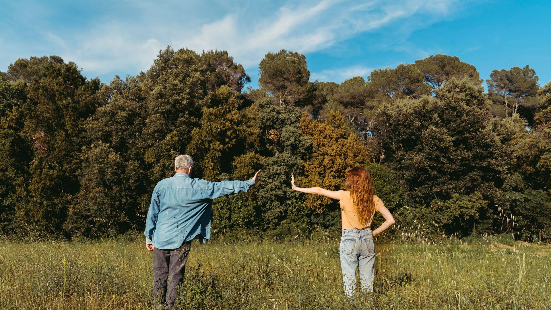 Mann und Frau stehen auf einer Wiese und zeigen eine armlänge Abstand zueinander Mann und Frau stehen auf einer Wiese und zeigen eine armlänge Abstand zueinander