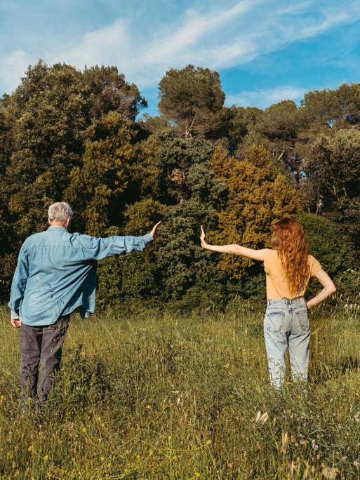 Mann und Frau stehen auf einer Wiese und zeigen eine armlänge Abstand zueinander Mann und Frau stehen auf einer Wiese und zeigen eine armlänge Abstand zueinander