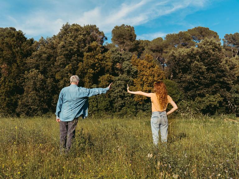 Mann und Frau stehen auf einer Wiese und zeigen eine armlänge Abstand zueinander Mann und Frau stehen auf einer Wiese und zeigen eine armlänge Abstand zueinander
