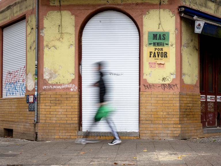 Verschommene Person geht an geschlossener Kneipe vorbei