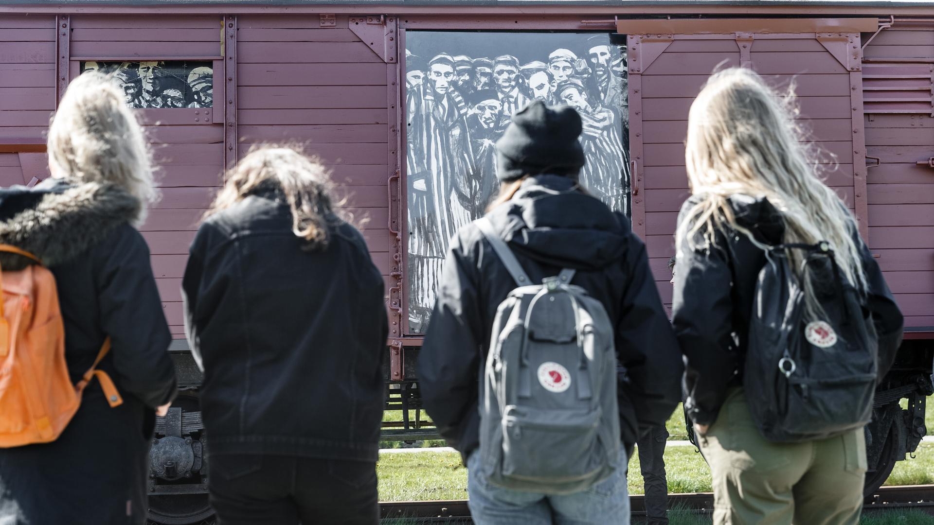 Schülerinnen betrachten einen historischen Reichsbahnwaggon im ehemaligen Lagerbahnhof des Konzentrationslagers Neuengamme steht