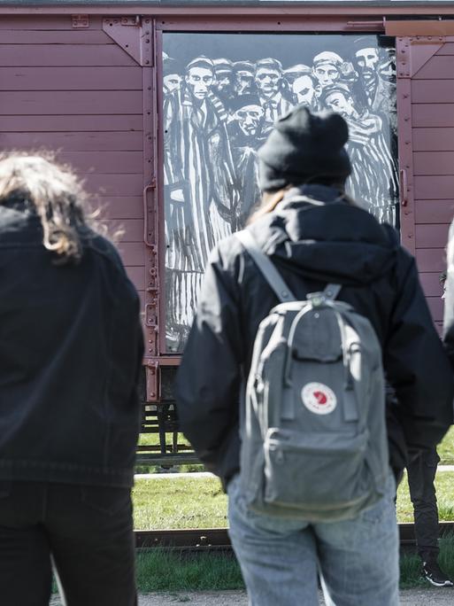 Schülerinnen betrachten einen historischen Reichsbahnwaggon im ehemaligen Lagerbahnhof des Konzentrationslagers Neuengamme steht