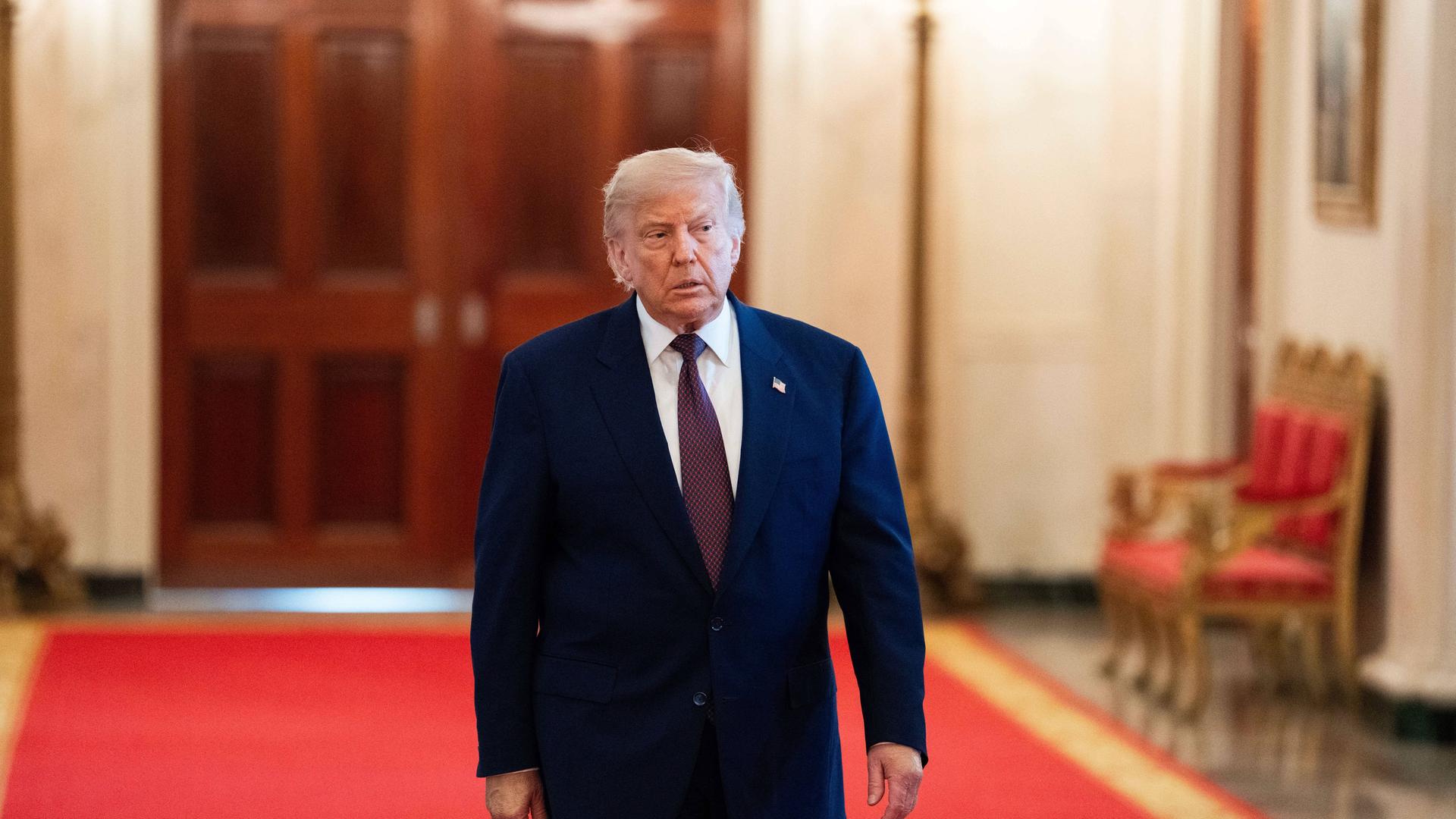Donald Trump geht über einen roten Teppich. Er trägt einen Anzug. Donald Trump geht über einen roten Teppich. Er trägt einen Anzug.