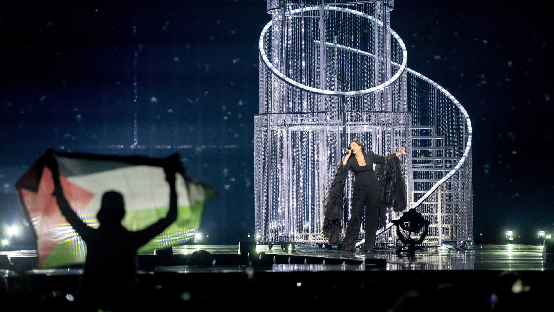 Ein Zuschauer hält eine palästinensische Flagge hoch, während Yuval Raphael bei der Generalprobe für das zweite Halbfinale des Eurovision Song Contests für Israel singt. Ein Zuschauer hält eine palästinensische Flagge hoch, während Yuval Raphael bei der Generalprobe für das zweite Halbfinale des Eurovision Song Contests für Israel singt.