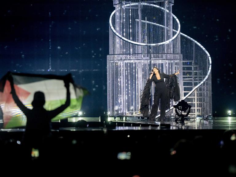 Ein Zuschauer hält eine palästinensische Flagge hoch, während Yuval Raphael bei der Generalprobe für das zweite Halbfinale des Eurovision Song Contests für Israel singt. Ein Zuschauer hält eine palästinensische Flagge hoch, während Yuval Raphael bei der Generalprobe für das zweite Halbfinale des Eurovision Song Contests für Israel singt.