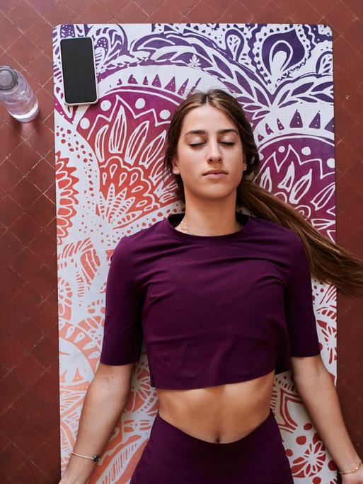 Eine Frau liegt auf einer Yogamatte