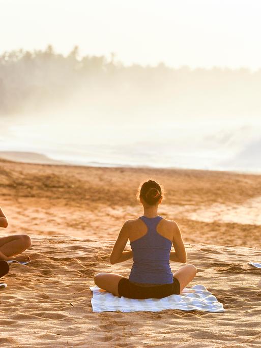 Eine Gruppe macht zusammen Yoga am Strand