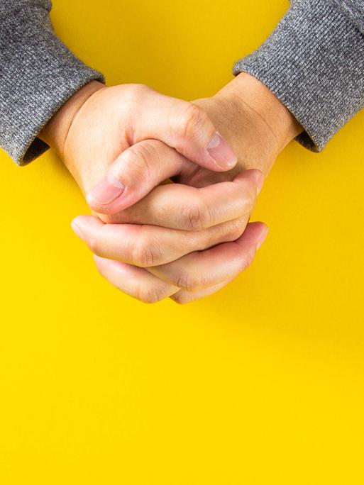 Die Hände des Mannes zum Gebet gefaltet auf gelben Hintergrund. Die Hände des Mannes zum Gebet gefaltet auf gelben Hintergrund.