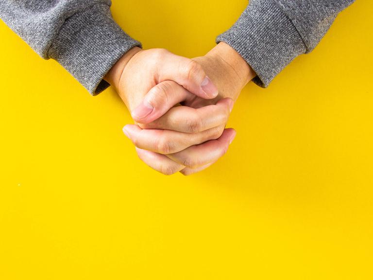 Die Hände des Mannes zum Gebet gefaltet auf gelben Hintergrund. Die Hände des Mannes zum Gebet gefaltet auf gelben Hintergrund.