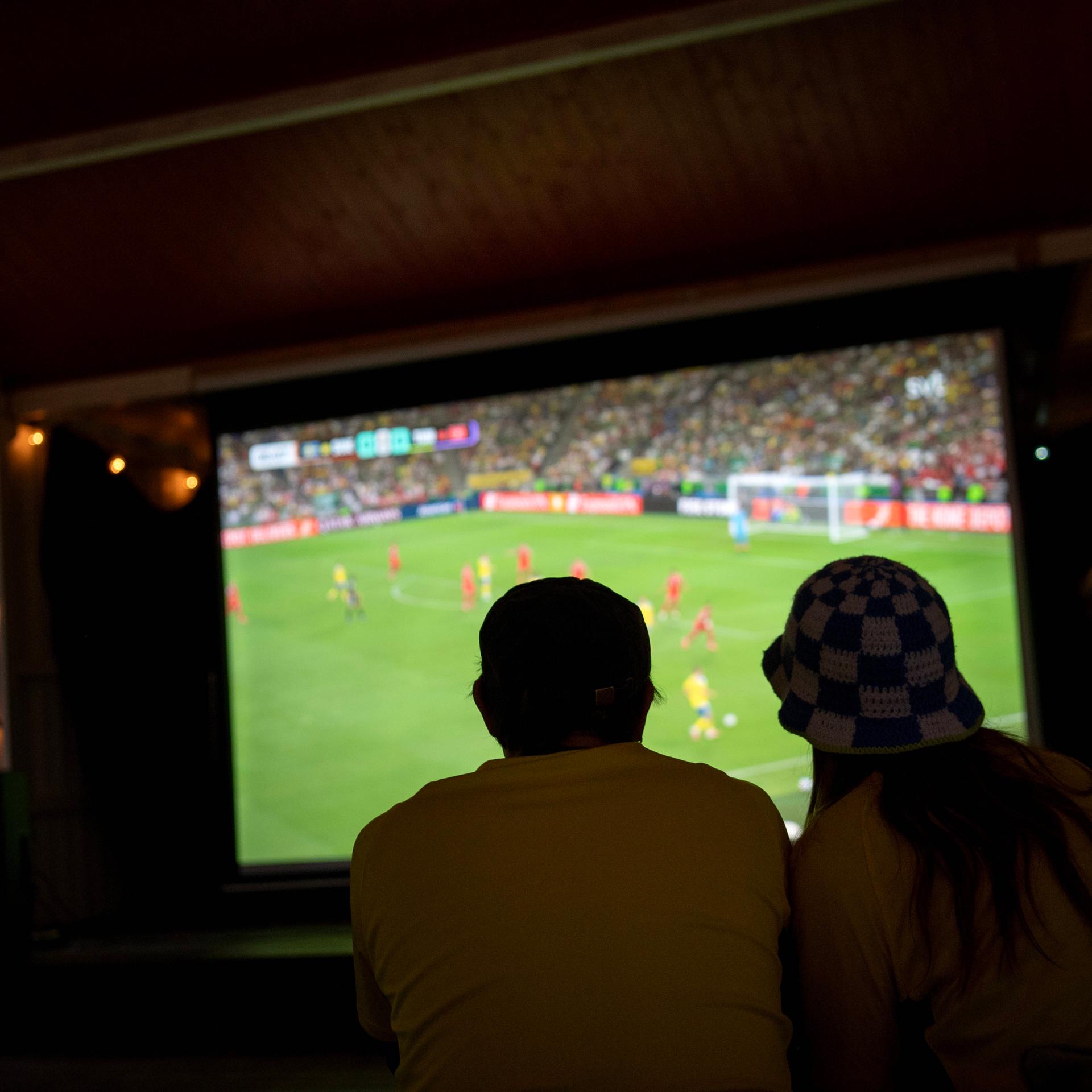 Fußballfans schauen ein Spiel der Fußball-Weltmeisterschaft auf einem großen Bildschirm