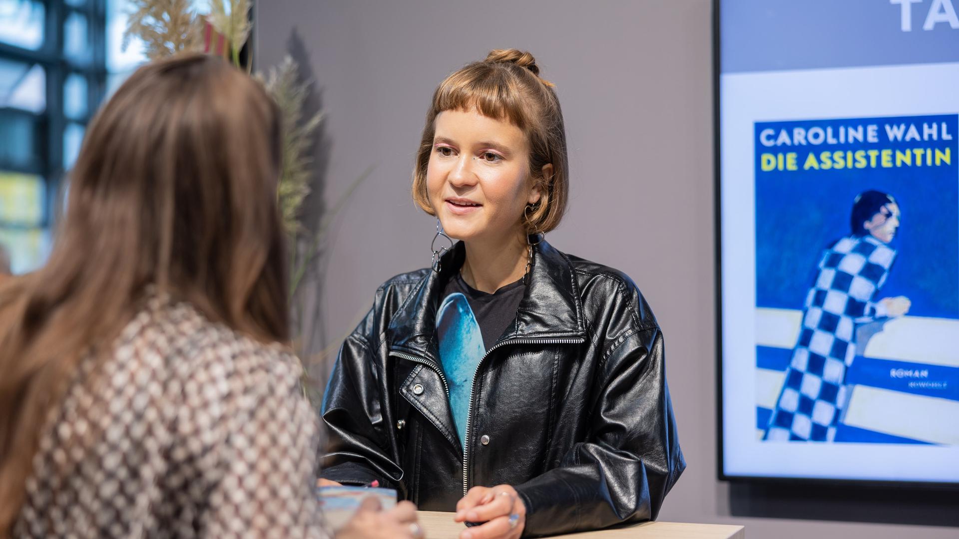 Autorin Caroline Wahl signiert an einem Stand auf der Buchmesse Frankfurt ihr neues Buch "Die Assistentin".