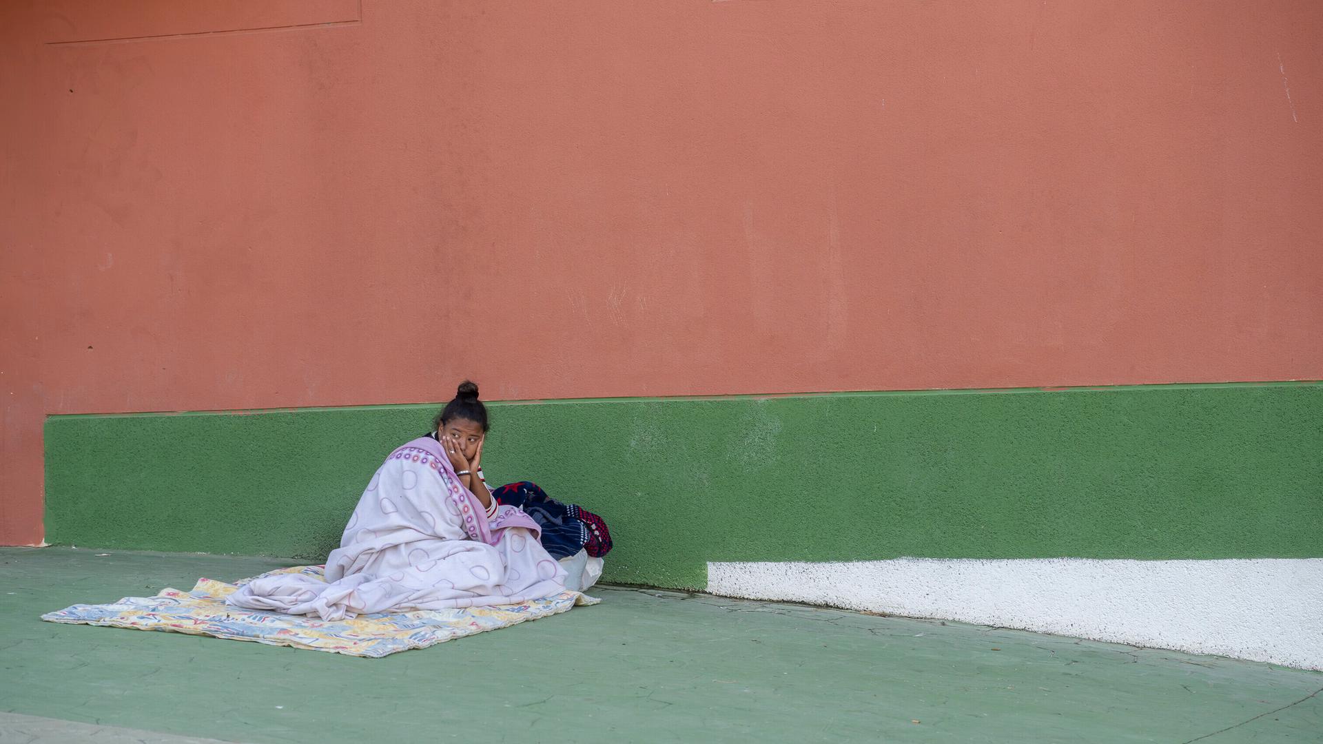 Junge Frau, in Decken gehüllt, sitzt an einer Wand in Ceuta (Spanien, 24.08.2026) Junge Frau, in Decken gehüllt, sitzt an einer Wand in Ceuta (Spanien, 24.08.2026)