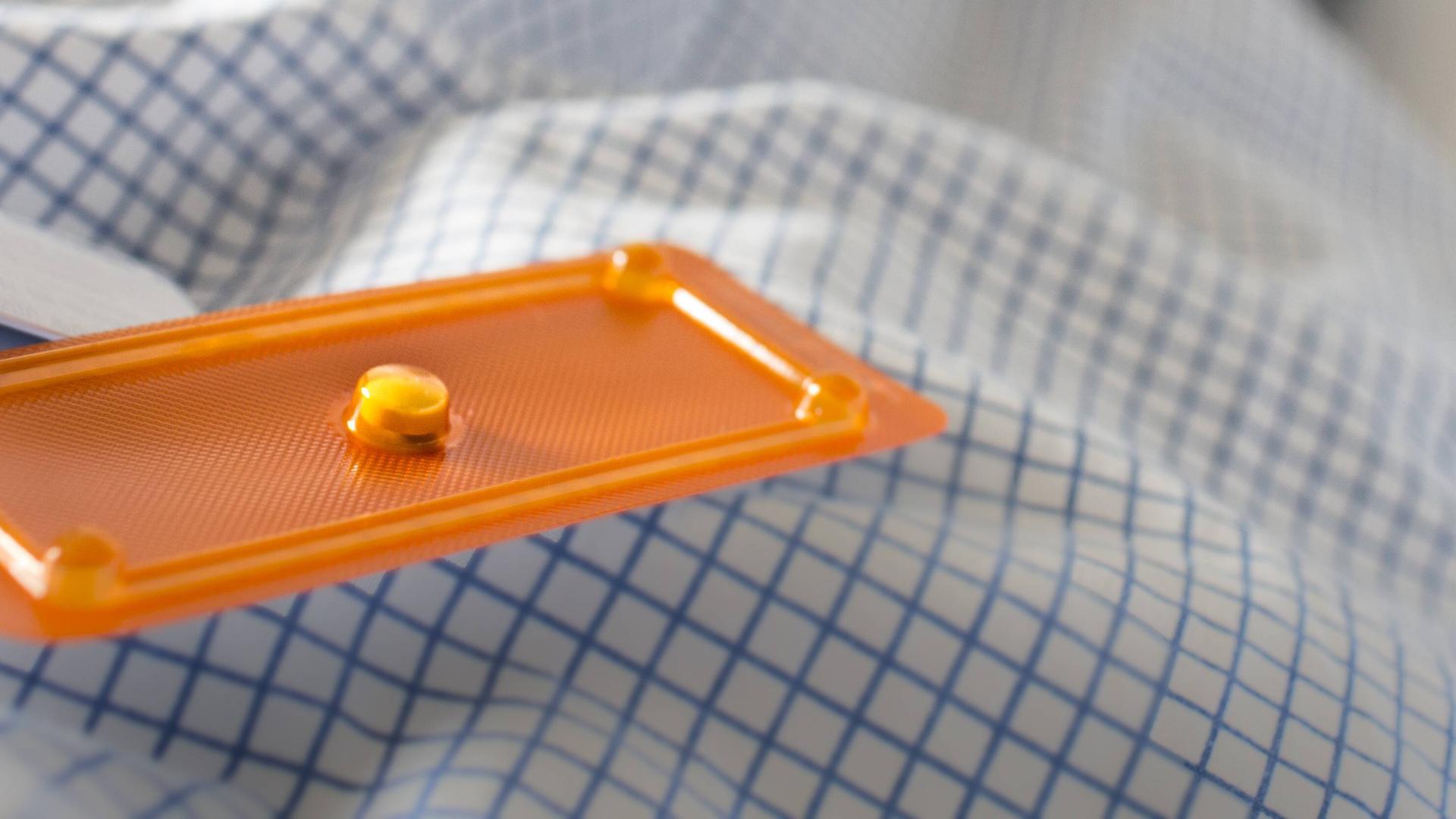 Ein Exemplar der sogenannten Pille danach liegt auf einer Bettdecke