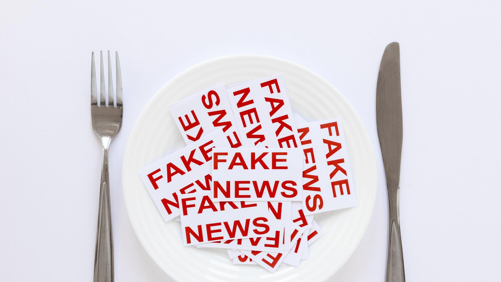 Teller auf dem Streifen mit der Aufschrift Fake News platziert sind Teller auf dem Streifen mit der Aufschrift Fake News platziert sind