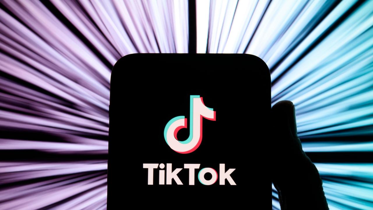 Illustration: TikTok-Logo auf einem schwarz gemalten Smartphone vor buntem Hintergrund