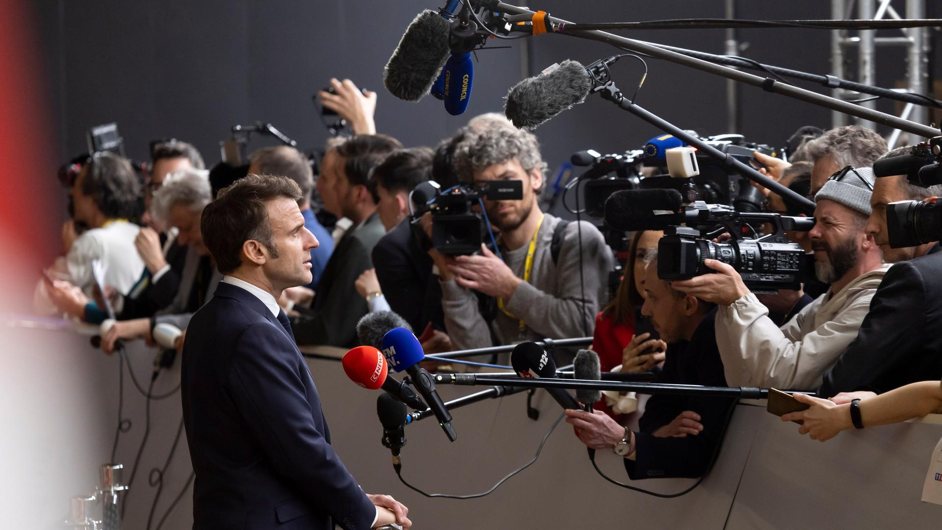 Emmanuel Macron gibt ein Pressestatement, vor ihm Kameras und Mikrofone