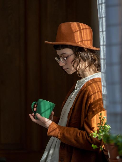 Eine Frau steht am Fenster und blickt traurig unten