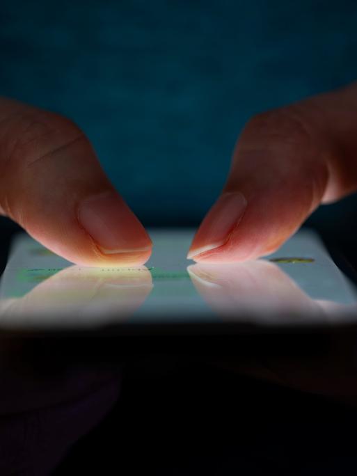 Ein Mensch hält ein Handy mit beiden Daumen auf dem Dsiplay