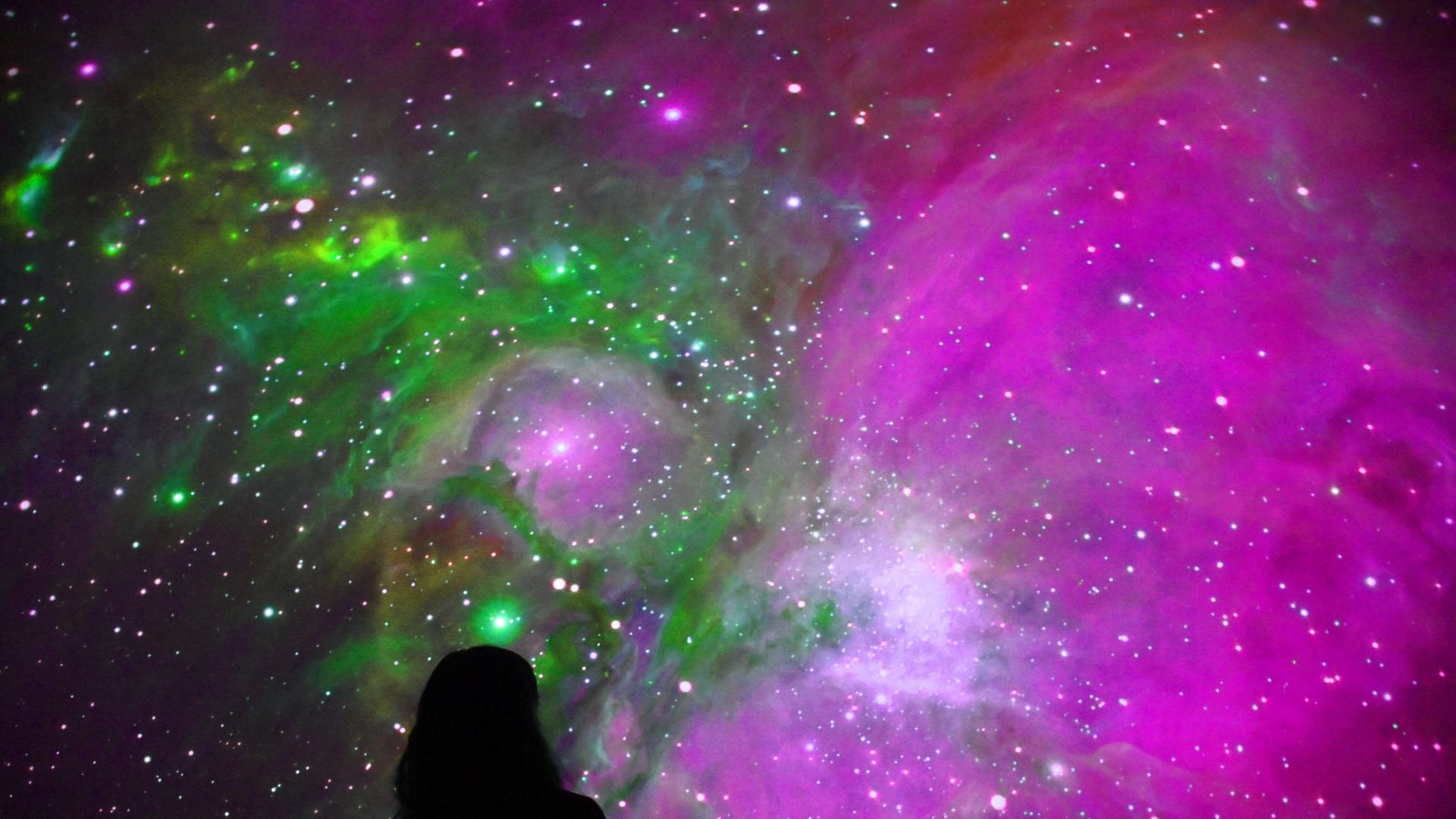 Eine Person betrachtet den Sternenhimmel in einem Planetarium
