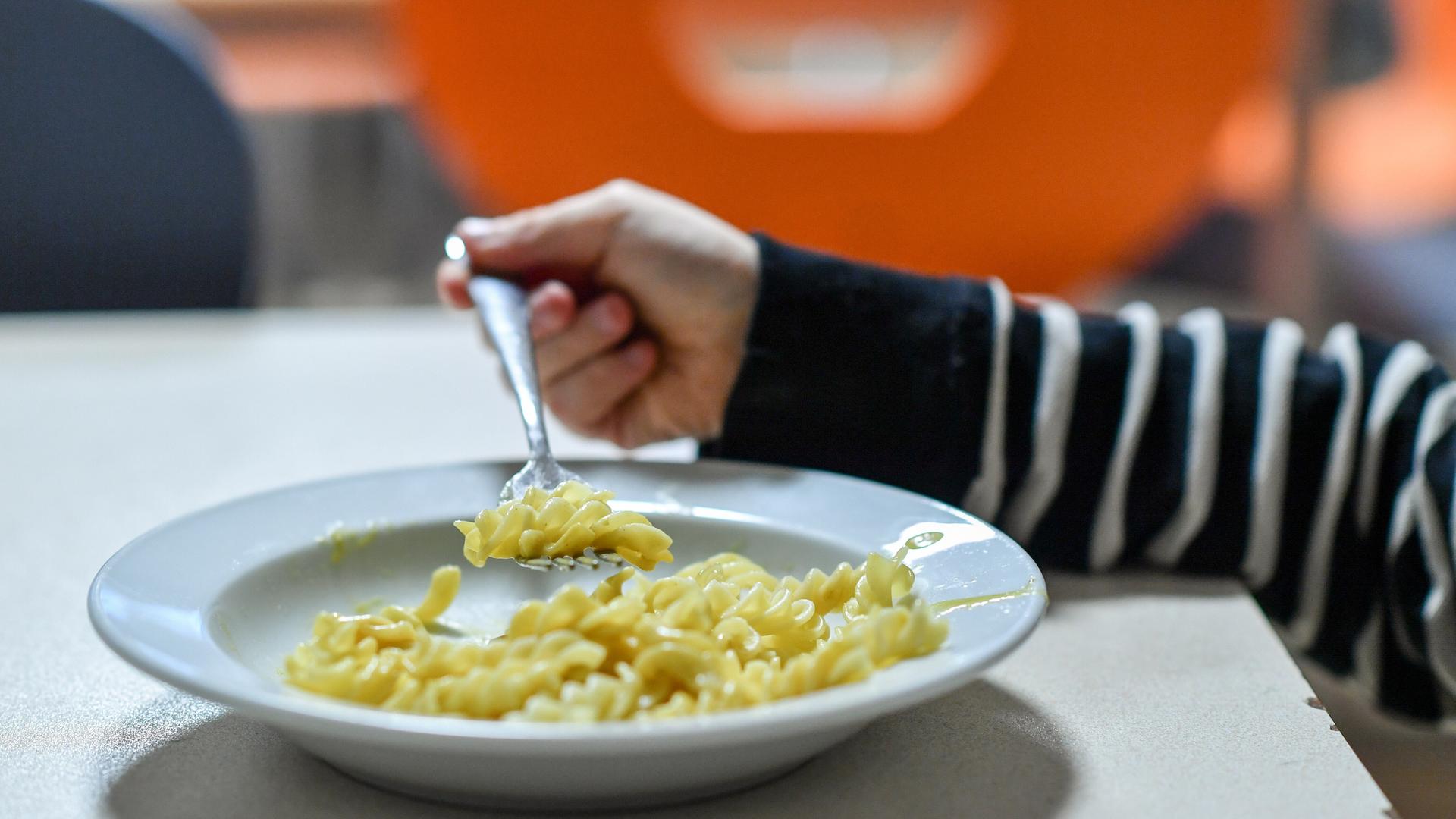 Ein Kind isst Nudeln von einem Teller. Ein Kind isst Nudeln von einem Teller.