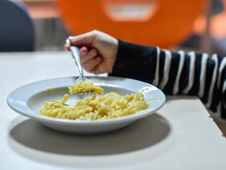 Ein Kind isst Nudeln von einem Teller. Ein Kind isst Nudeln von einem Teller.