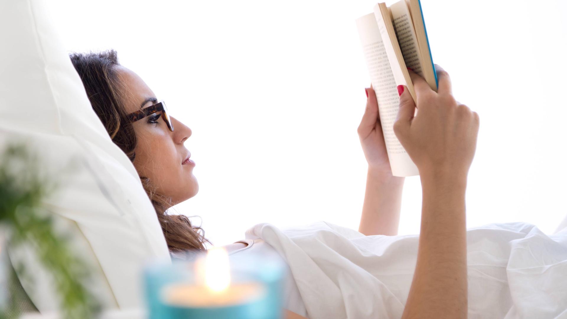 Eine Frau liegt im Bett und liest ein Buch