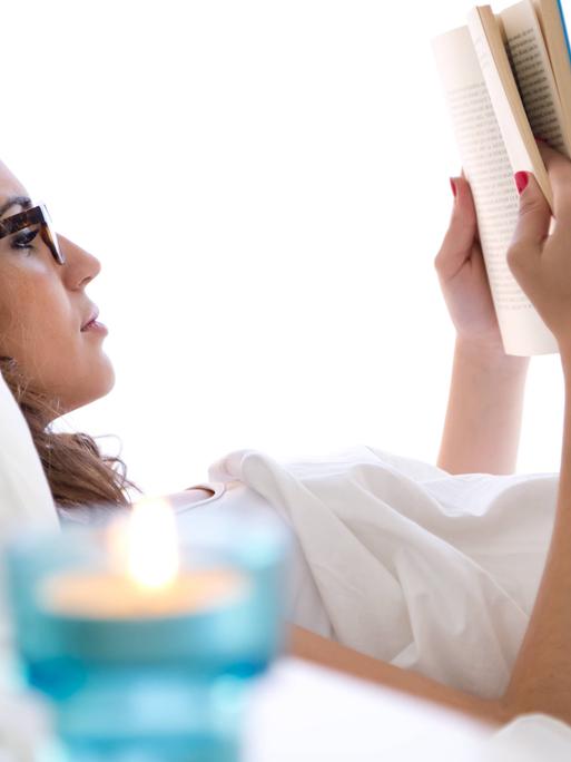 Eine Frau liegt im Bett und liest ein Buch
