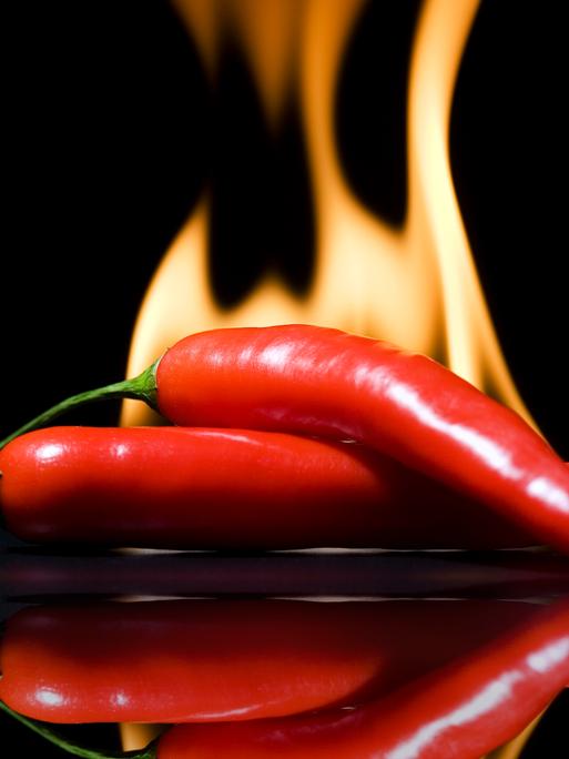 Zwei Peperonis vor Flammen im Hintergrund