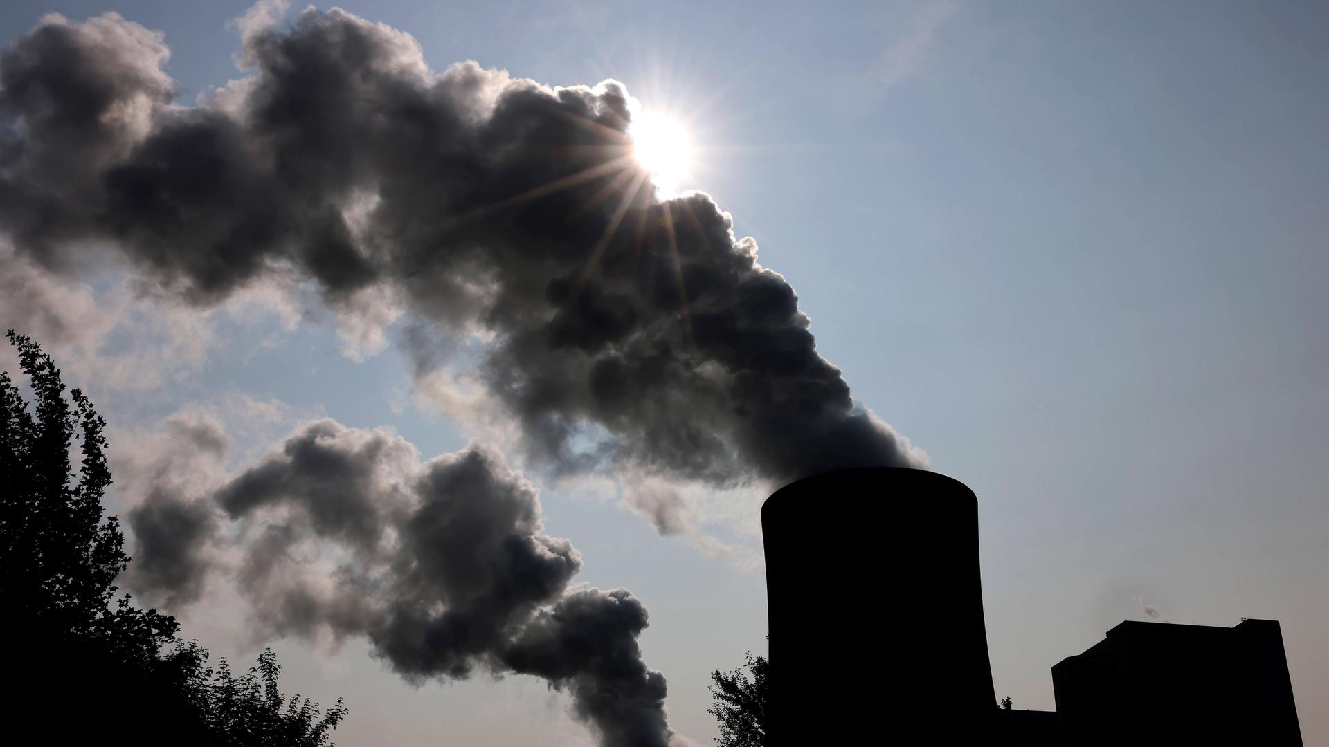 Das RWE-Kohlekraftwerk Neurath an einem sonnigen Vormittag. Die Sonne verschwindet hinter Emissionen aus den Kraftwerkstürmen.