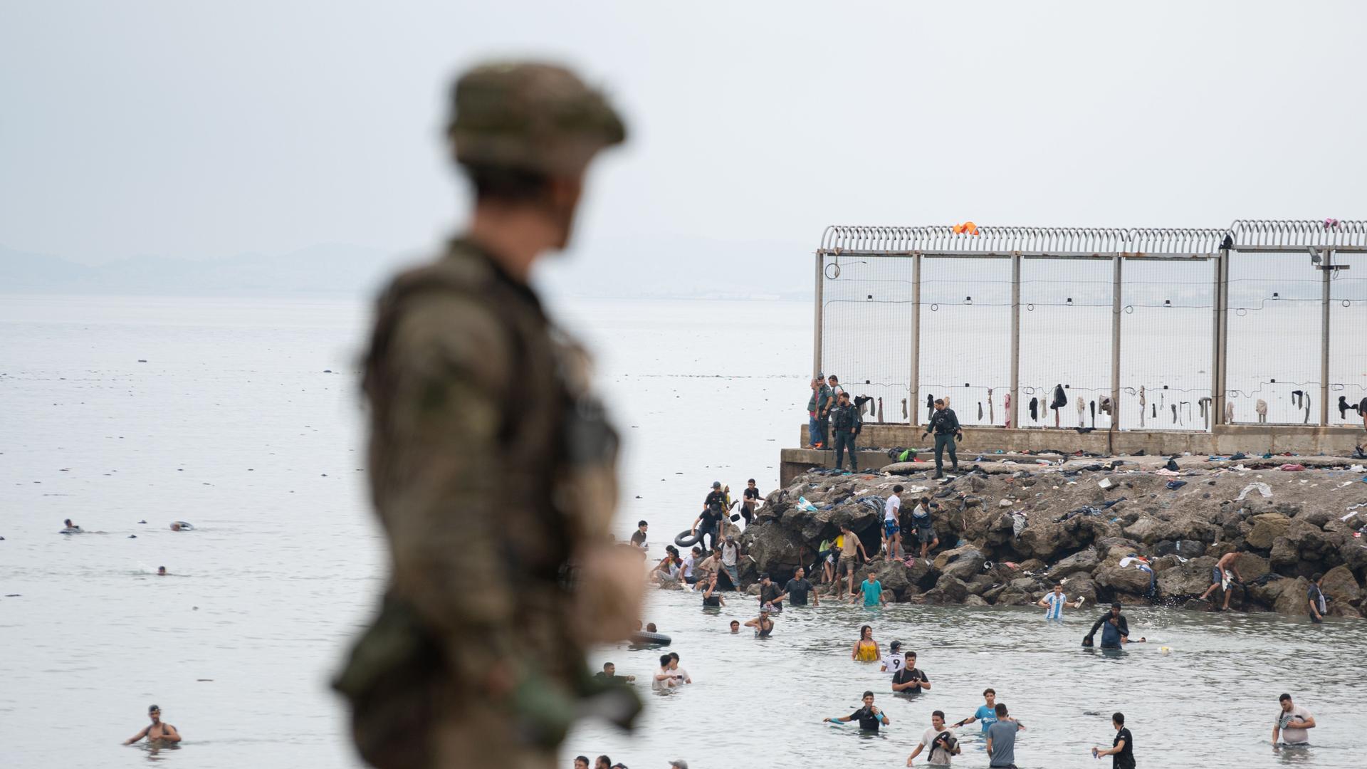 Ein spanischer Soldat mit Blick auf den Grenzzaun an der Küste Ceutas