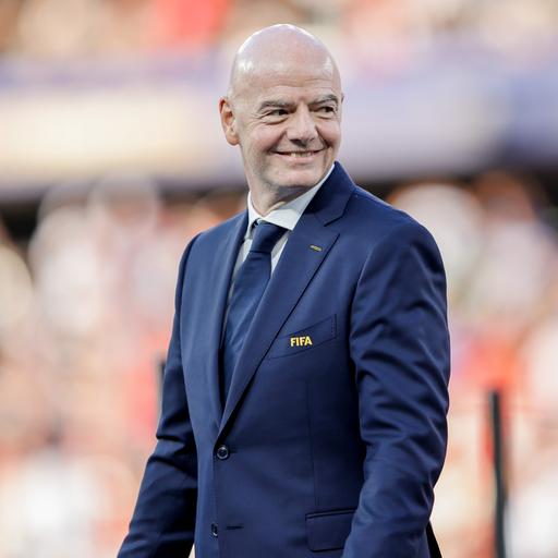 FIFA-Präsident Gianni Infantino läuft über das Fußballfeld beim WM-Spiel Spanien gegen Argentinien und lächelt.