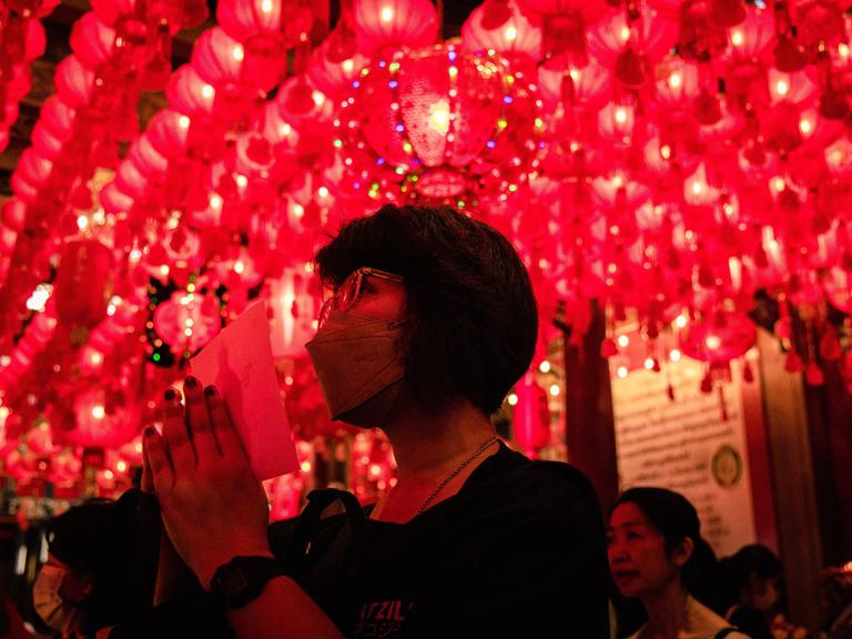In einem buddhistischen Tempel in Bangkok (Thailand) hält eine Frau die Hände zum Gebet zusammen.