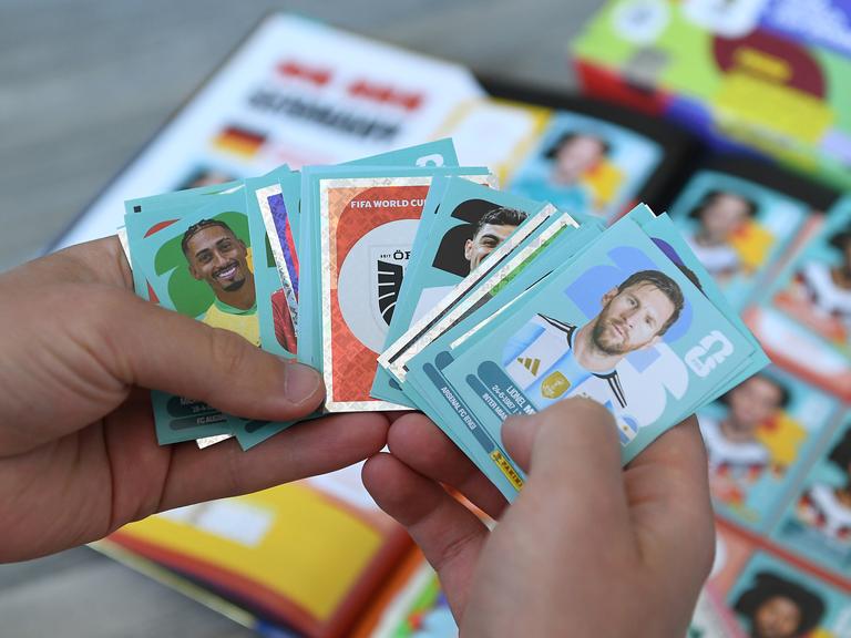 Eine Person hält Panini-Sticker in den Händen