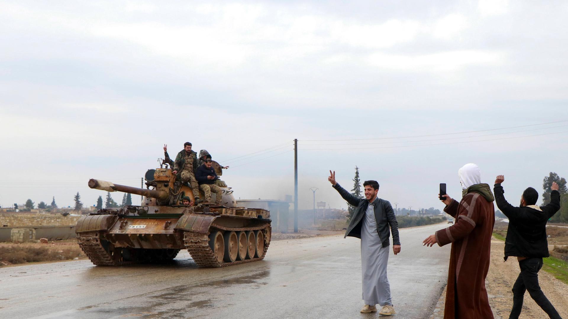 Menschen jubeln bei Rakka einem Panzer der Armee zu.
