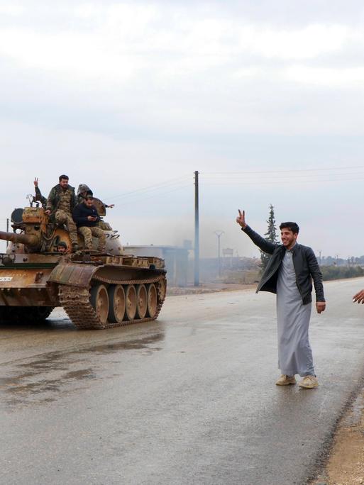 Menschen jubeln bei Rakka einem Panzer der Armee zu.